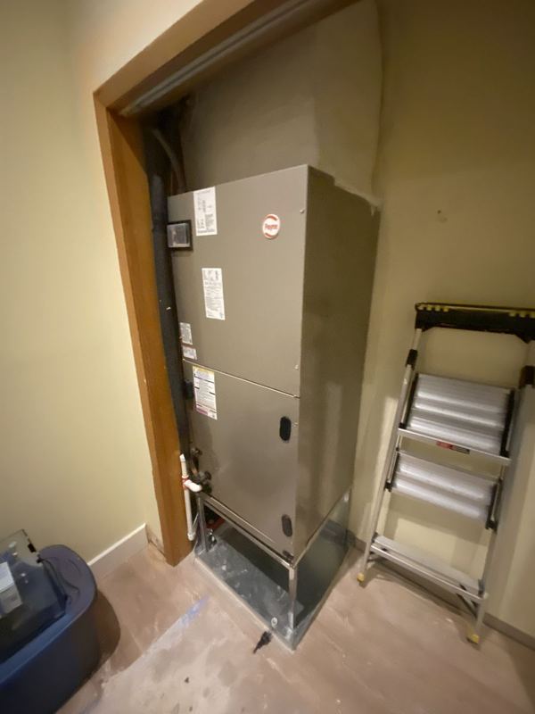 Air handler installed on a metal stand inside an interior utility closet