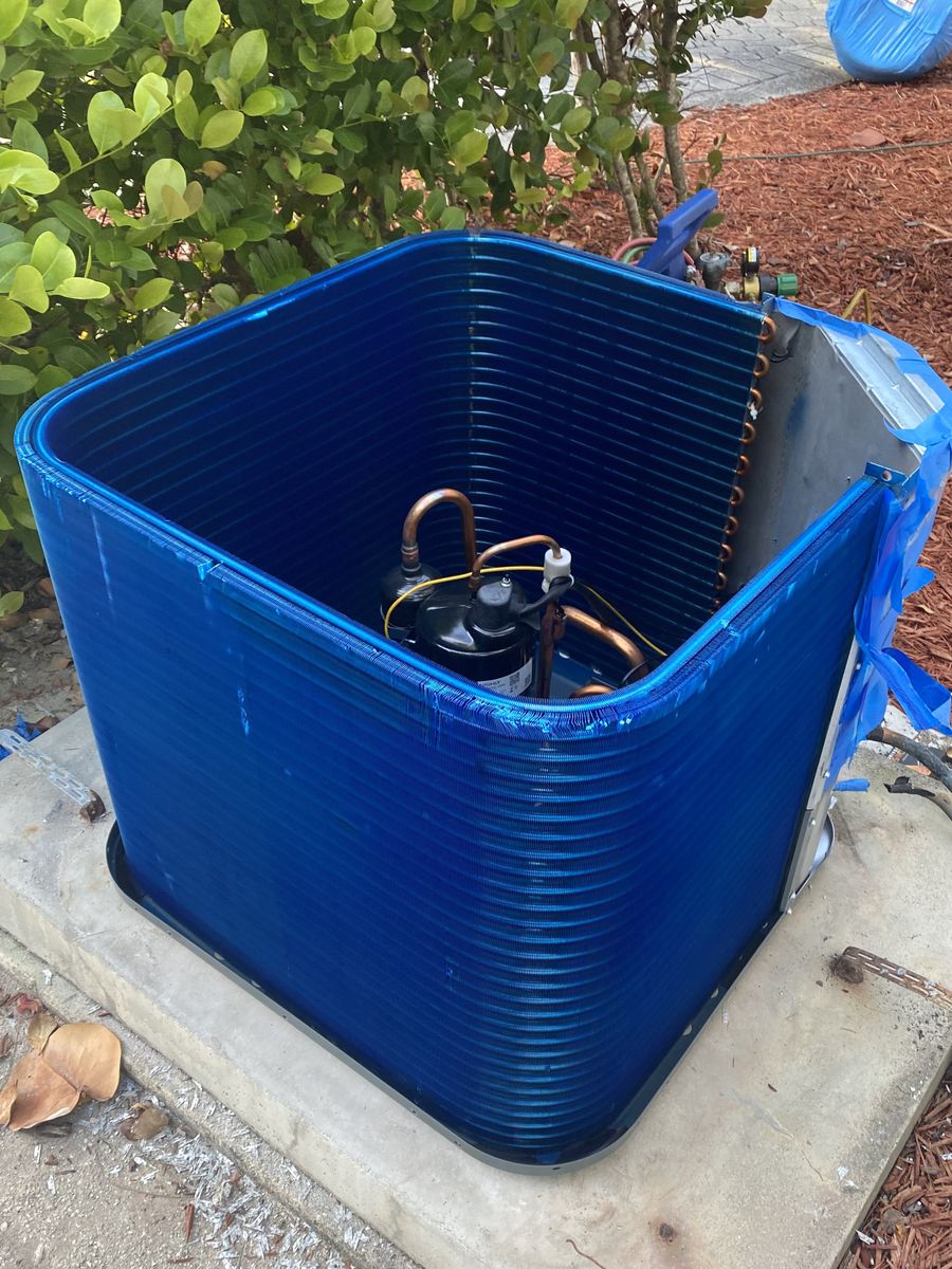 Coastal-proofing job: condenser coil coated in blue protective anti-corrosion coating, top removed showing the compressor