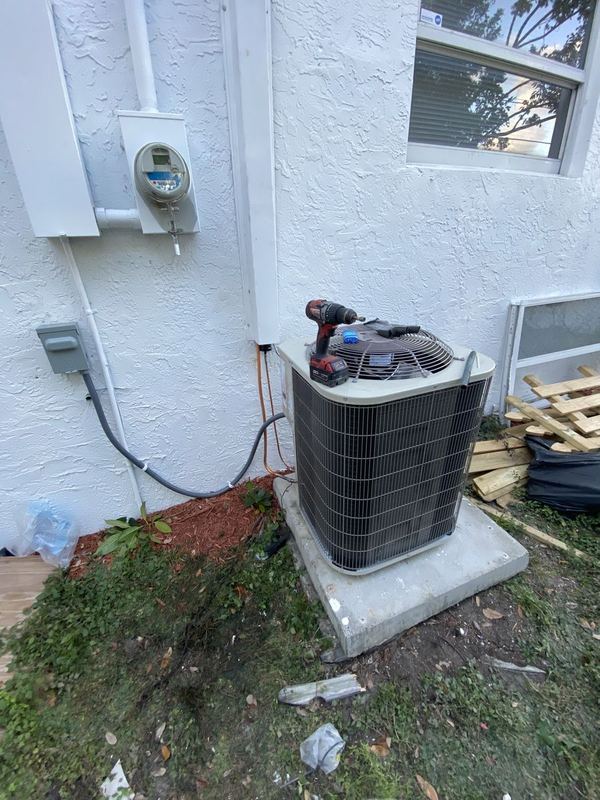 Newly installed AC condenser on a concrete pad next to a white stucco wall and electric meter
